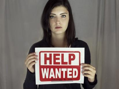 person holding help wanted sign