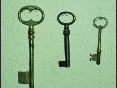 three keys, hanging next to each other on a green background