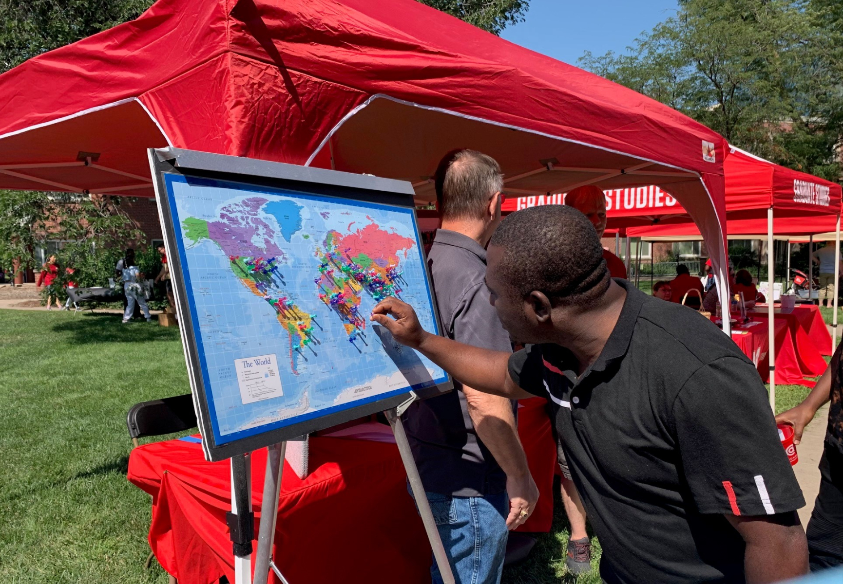 Graduate student adding home location pin to a world map at the Welcome Resource Fair.