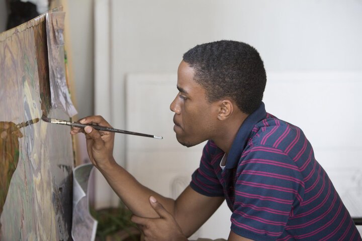 Graduate student painting on easel