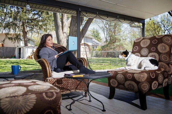 Graduate student working on a laptop at home on the patio with dog